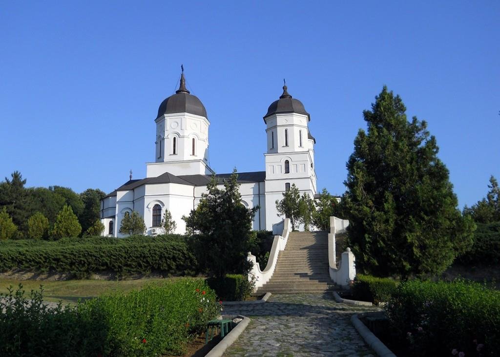Biserica albă a Mănăstirii Celic Dere, cu două turle și scări de acces, între copaci