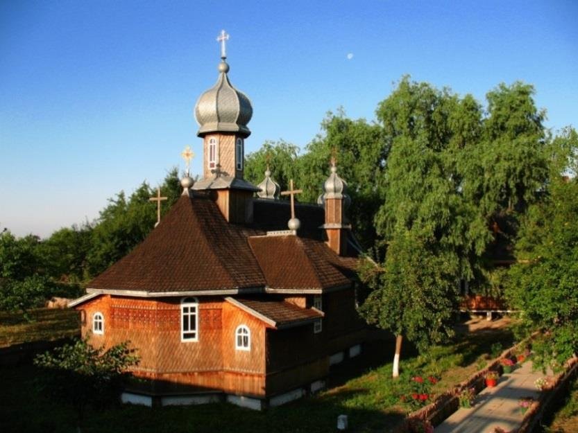 Biserica de lemn a schitului de pe grindul Stipoc, cu acoperiș de șindrilă, între copaci