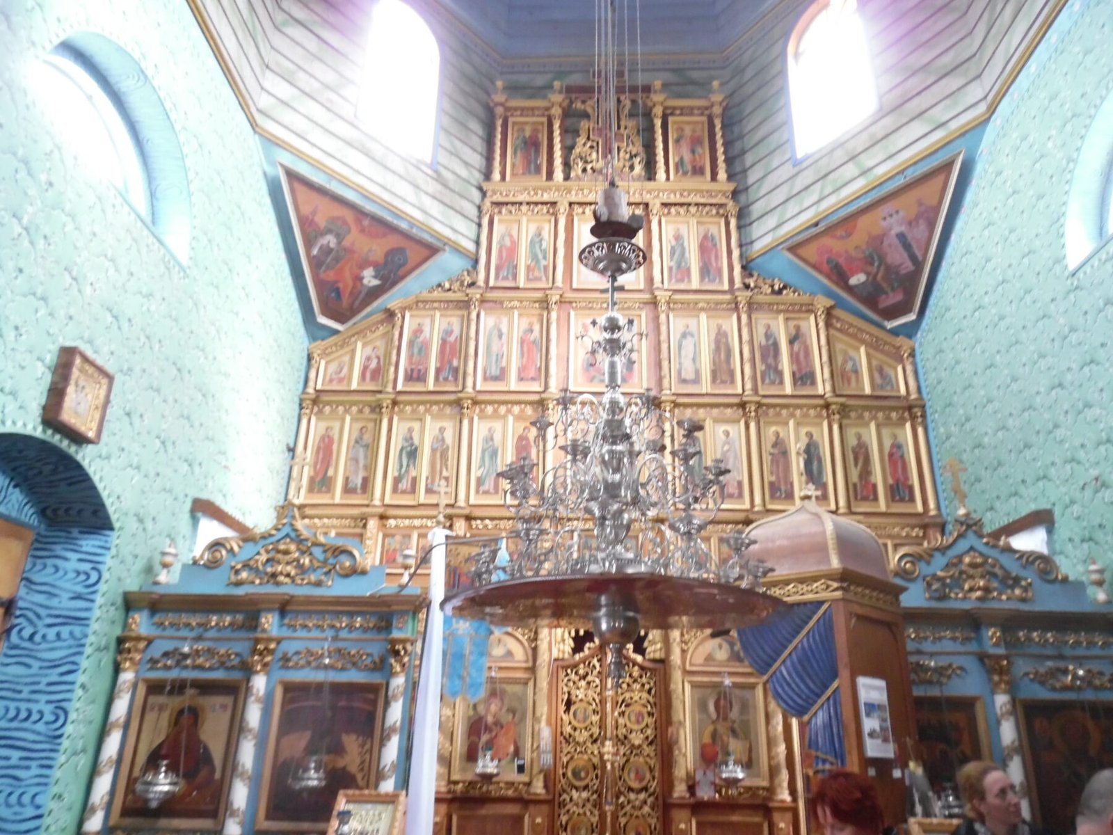 Catapeteasma Mănăstirii Uspenia din Slava Rusă, cu icoane aurite pe mai multe registre și candelabru în față