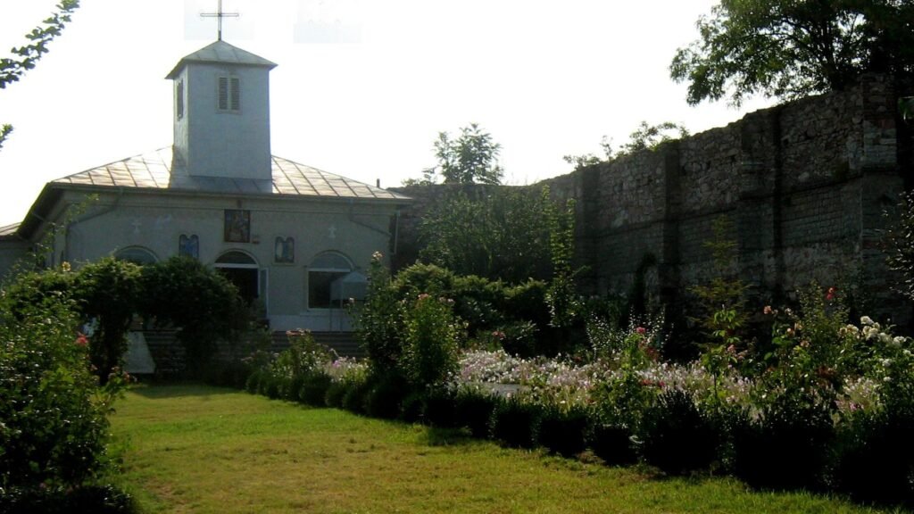 Biserica Sfântul Gheorghe din Isaccea, cu turnul-clopotniță deasupra intrării, văzută peste grădină