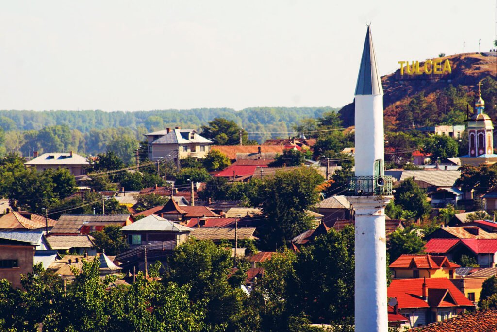 Minaretul geamiei Azizie deasupra acoperișurilor din Tulcea, cu dealul Hora în spate