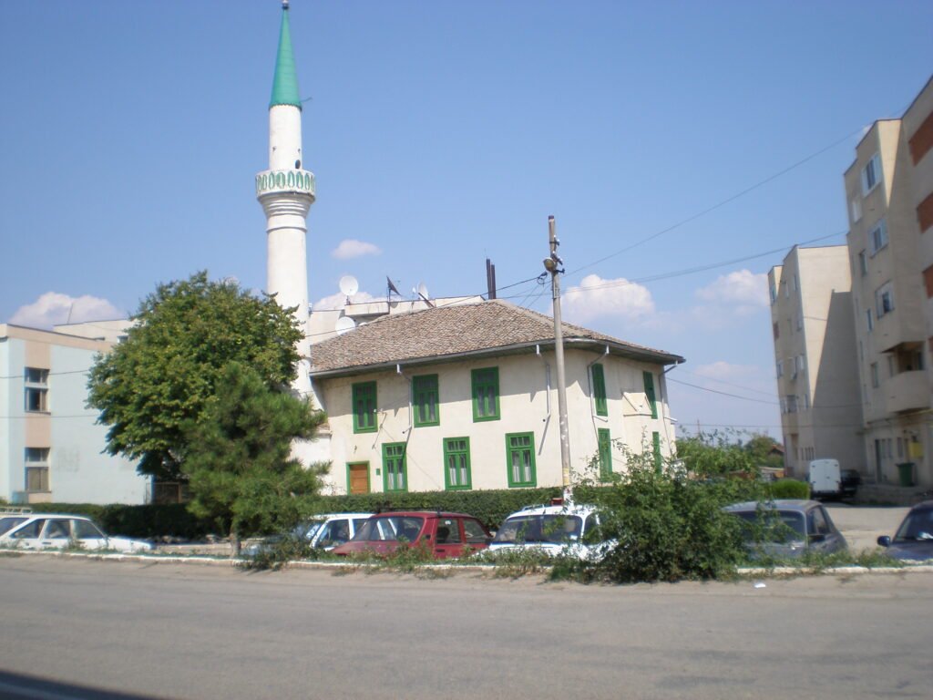 Geamia din Isaccea văzută din lateral, cu ferestre verzi și minaretul alb