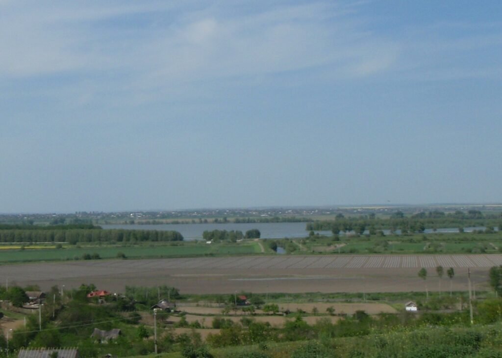Vedere de pe dealul de la vest de Isaccea, spre Revărsarea: câmpuri, lunca Dunării și fluviul, spre malul ucrainean (Orlivka, după descrierea de pe Commons)